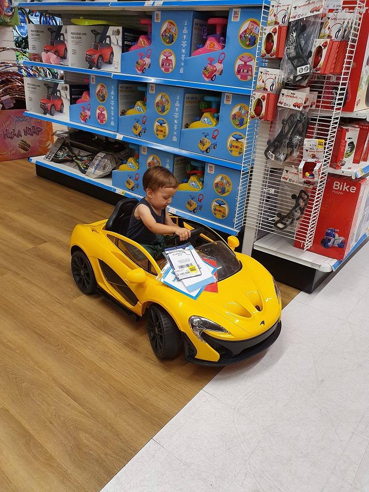 Arthur sitting in a toy car at the store